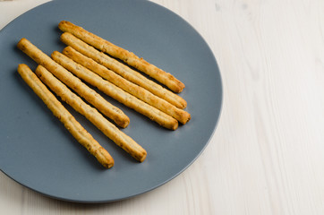 rustic breadsticks in a dish on wood table, close up, background
