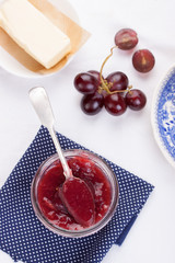 Jam with red grape in a glass jar on a white background. Top view.