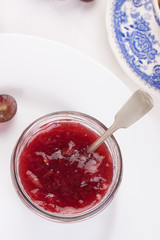 Jam with red grape in a glass jar on a white background. Closeup.