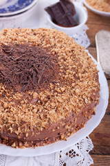 Chocolate truffle cake with сrushed peanuts and cacao on a wooden background. Closeup.