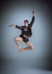 The young attractive modern ballet dancer jumping on gray background