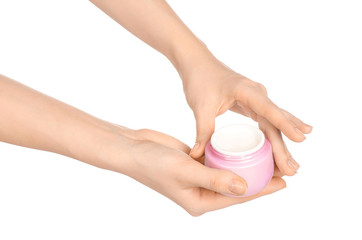 Body care and health topic: a woman's hand holding a pink jar of cream isolated on white background in studio