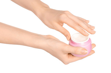 Body care and health topic: a woman's hand holding a pink jar of cream isolated on white background in studio