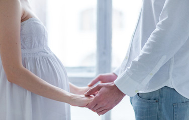 The young couple  dressed in white standing at home