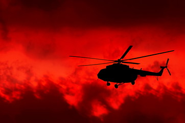 helicopter on a background of fire sky
