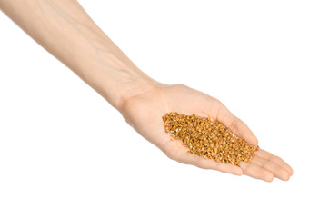 Groats and meal preparation topic: human hand holding a pile of buckwheat isolated on a white background in studio