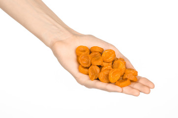 Dried fruits and meal preparation topic: human hand holding an orange dried apricots isolated on white background in studio