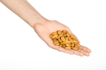 Nuts and cooking theme: man's hand holds nuts almonds on a white isolated background in studio