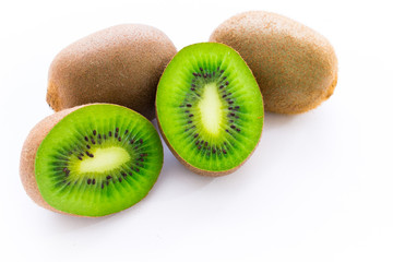 Close up photo of two cut-in-half slices of kiwi, with two whole kiwis behind. The background is isolated.