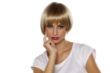 Serious young woman with short blonde wig posing on a white