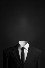 Surrealismus und Business-Thema: ein Mann ohne Kopf in einem schwarzen Anzug auf dunklem Hintergrund im Studio © Alex