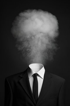 Surrealism and business topic: the smoke instead of a head man in a black suit on a dark background in the studio