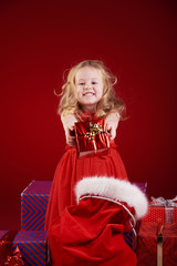Lovely little girl with Christmas presents on a red background.