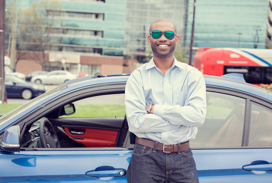 Happy man driver smiling standing by his new sport blue car