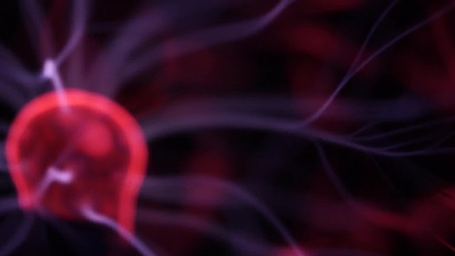Closeup view of plasma ball with moving energy rays inside on black background 