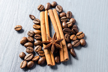Coffee beans, cinnamon sticks and star anise on gray wooden table