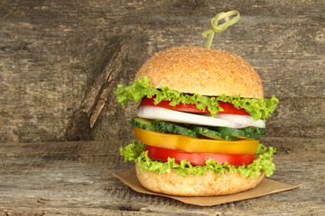 Healthy vegan burger with raw vegetables on old wooden background.