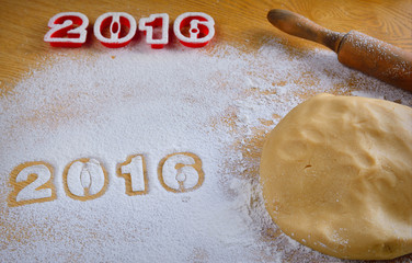 Dough, flour and rolling pin on wooden table with numbers 2016