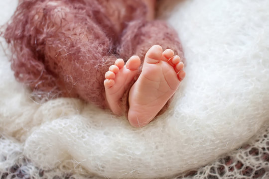 Close up picture of new born baby feet on a brown plaid