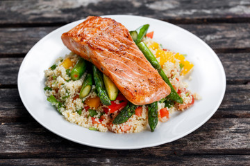 Pan fried salmon with tender asparagus and courgette served on couscous mixed with sweet tomato,...