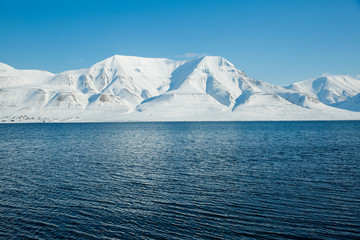 The waves of the Arctic Ocean and the snow-capped mountains of the Spitsbergen archipelago.
