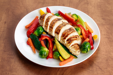 Grilled chicken fillet, breast with cooked vegetable  on plates.