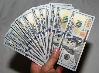 The hand holds a thousand and four hundred dollars