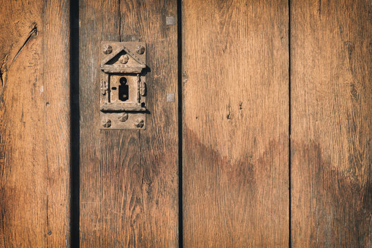 Old, vintage cellar wood door with a rusty and decorated keyhole
