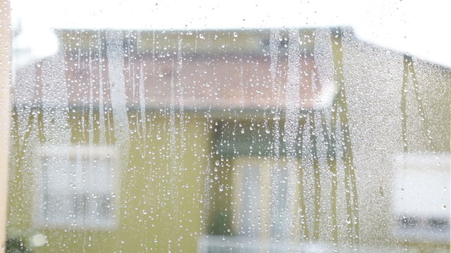 Vetro bagnato dopo la pioggia con lo sfondo sfuocato di alcune case di una citt&agrave;