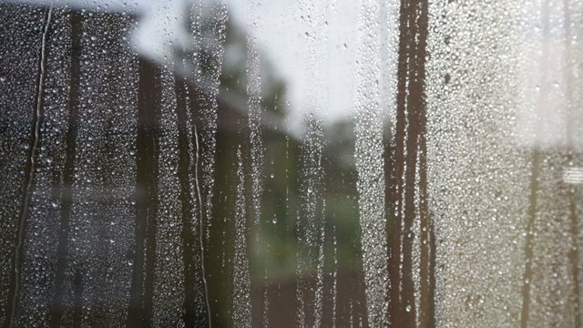 Vetro bagnato dopo la pioggia con lo sfondo sfuocato di alcune case di una citt&agrave;