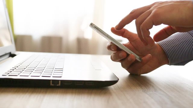 mani di uomo di carriera in ufficio con smartphone e notebook