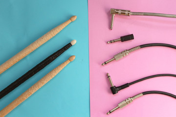Drum sticks on blue background and audio plug on pink background