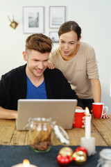 glückliches junges paar mit laptop in der weihnachtszeit