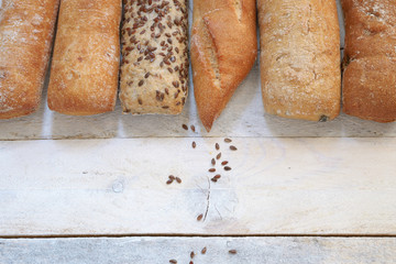 Assortment of baked bread on a white wood table. Copy space for editor's text. Top view