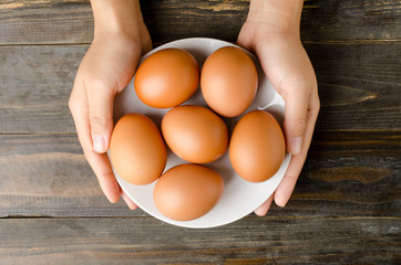 Eggs on white plate and hold by hand on wooden background