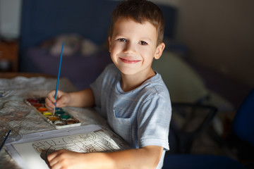 Little boy painting at home by watercolor