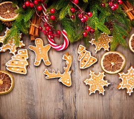 Christmas holiday border with gingerbread cookies, candy cane over wooden background