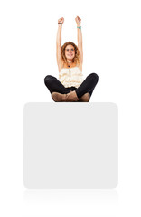 young woman sitting on a white box celebrating something
