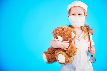 Beautiful doctor, nurse examines teddy bear on a blue background