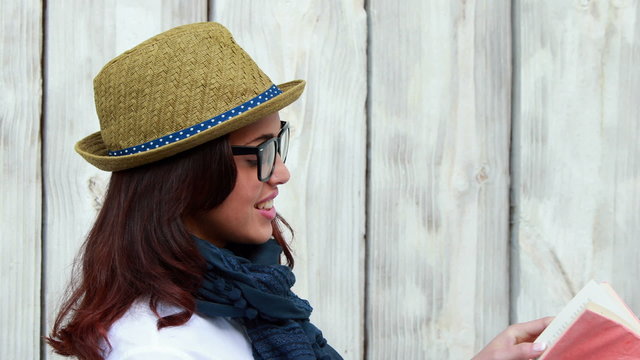 Smiling hipster woman reading a book