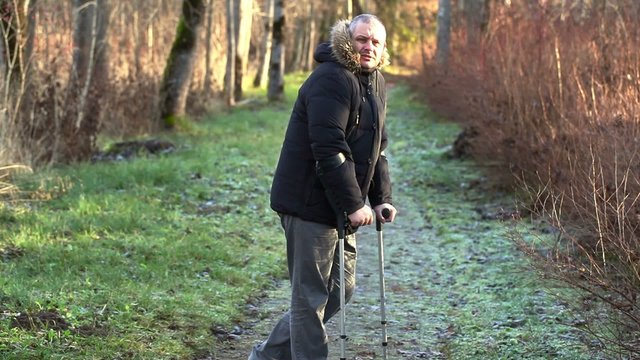 Disabled man on crutches on path