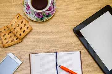 Wooden table with table pc, tea and office supplies, top view