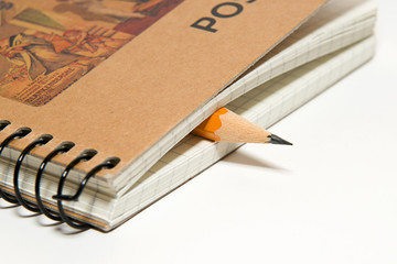 Closed notebook  and pencil on over white