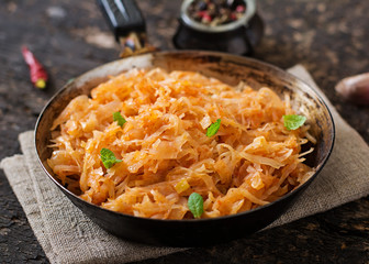 Stewed cabbage on the old wooden background in rustic style
