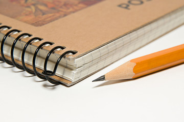 Closed notebook  and pencil on over white