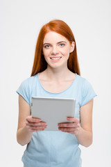 Naklejka premium Pretty smiling redhead lady with long hair using tablet isolated