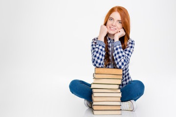 Beautiful happy young redhead girl sitting and posing with books