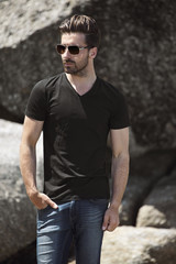 Young man in black t-shirt posing on rocks