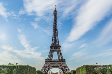 Eiffel Tower againt a blue sky, with wispy clouds