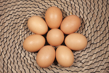 Eight chicken's eggs on wicker background.